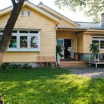 charming-yellow-house-with-wooden-windows-green-grassy-garden